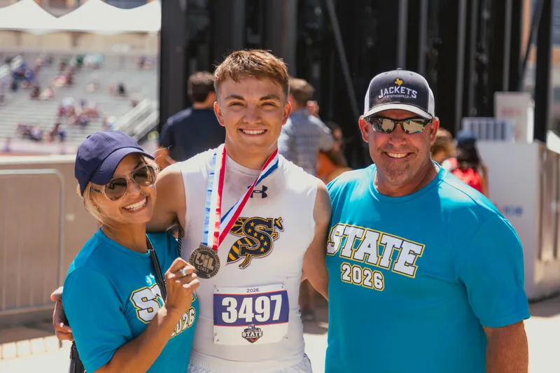 Kylar Mills holding his state medal with his parents at the UIL State Championships